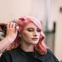 Stylist completing hairdressing service on lady with pink hair